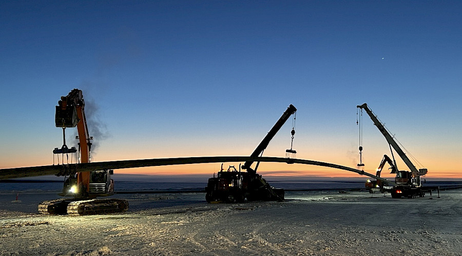 Excavator and truck working at night on frozen lake during Frog Lake construction project