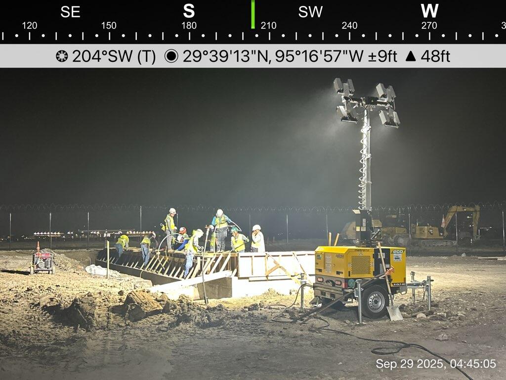 Multiple hybrid light towers lighting a large Houston airport construction area to support continuous night work.
