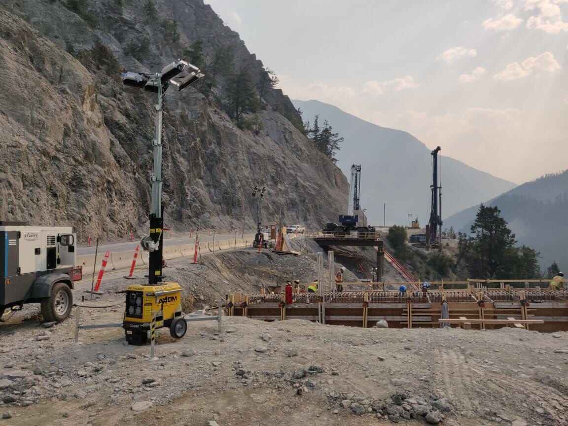 Electric light tower providing diesel-free lighting on a tunnel construction project in a mountainous worksite environment.